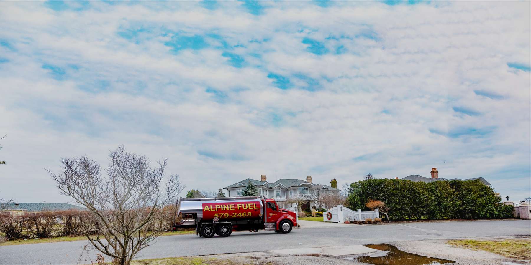 Residential heating oil truck parked in front of a gray shingle style home with cobblestone driveway in Central Islip, Long Island, New York delivering fuel oil. Residential heating oil truck parked in front of a gray shingle style home with cobblestone driveway in Central Islip, Long Island, New York delivering fuel oil.