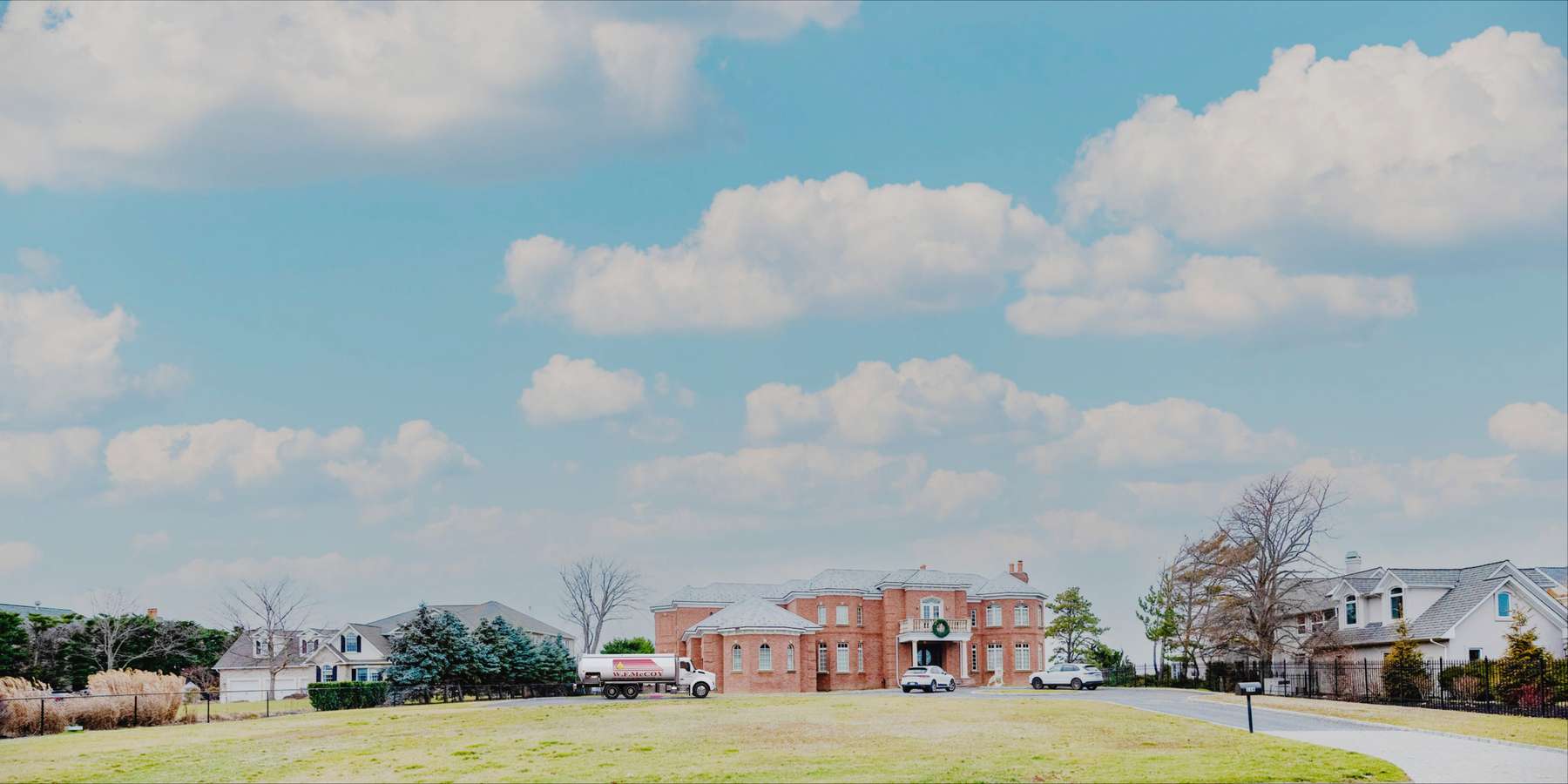 Residential heating oil truck in front of a brick mansion in Bridgehampton, Long Island, New York delivering fuel oil. Residential heating oil truck in front of a brick mansion in Bridgehampton, Long Island, New York delivering fuel oil.