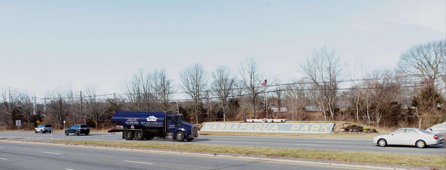 Residential heating oil truck with the town welcome sign and an American flag in Massapequa Park, Long Island, New York delivering fuel oil. Residential heating oil truck with the town welcome sign and an American flag in Massapequa Park, Long Island, New York delivering fuel oil.